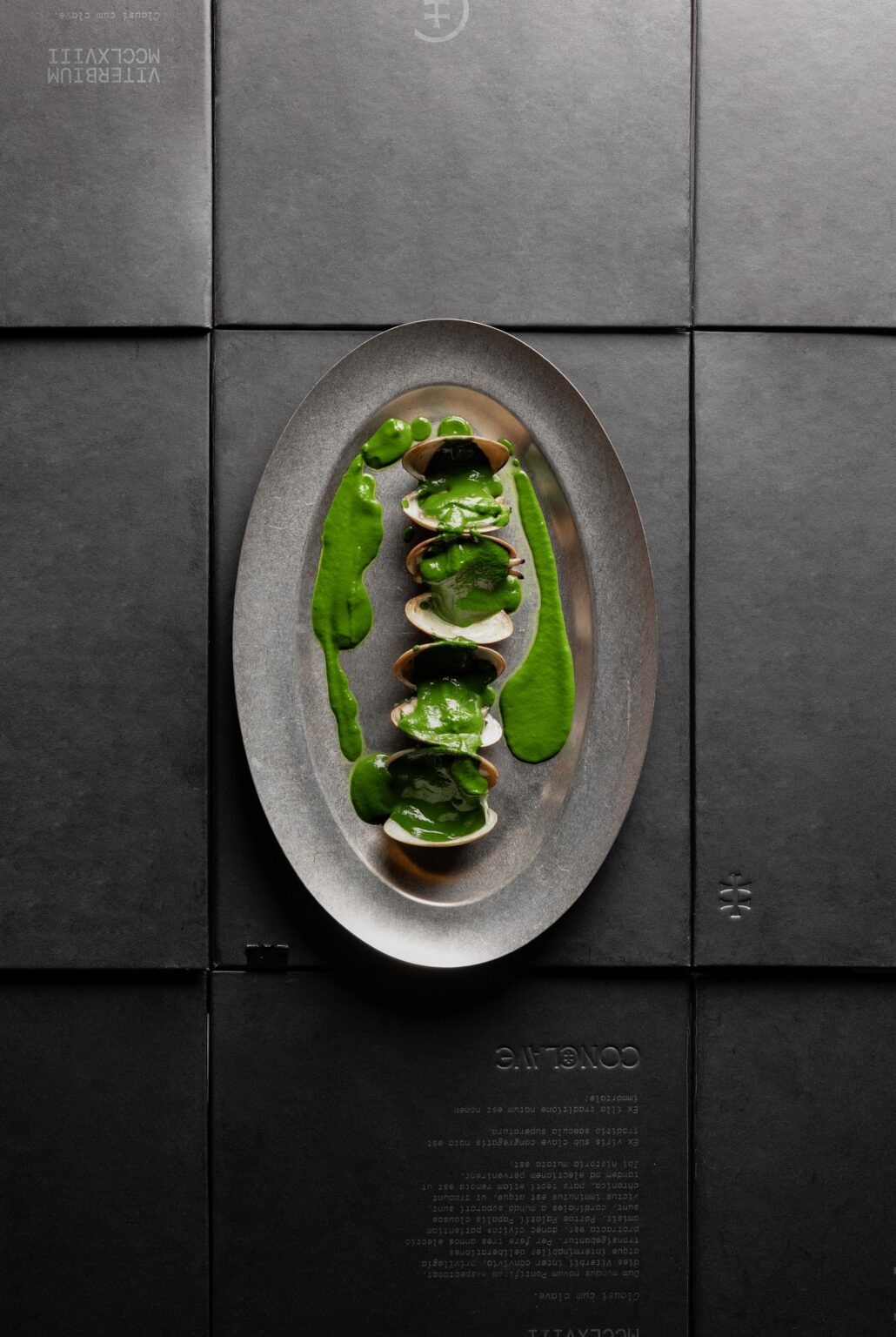 Almejas de Carril a la brasa con salsa verde en bandeja ovalada de metal, vista cenital